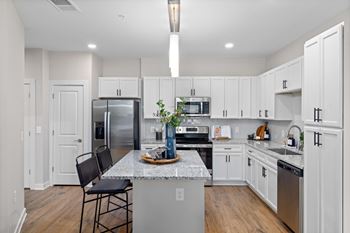 A kitchen with white cabinets and a marble countertop.